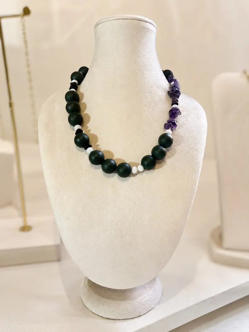 Colar de bolas verde-escuras com pedras de quartzo lilás e apatitas brancas, num busto de veludo