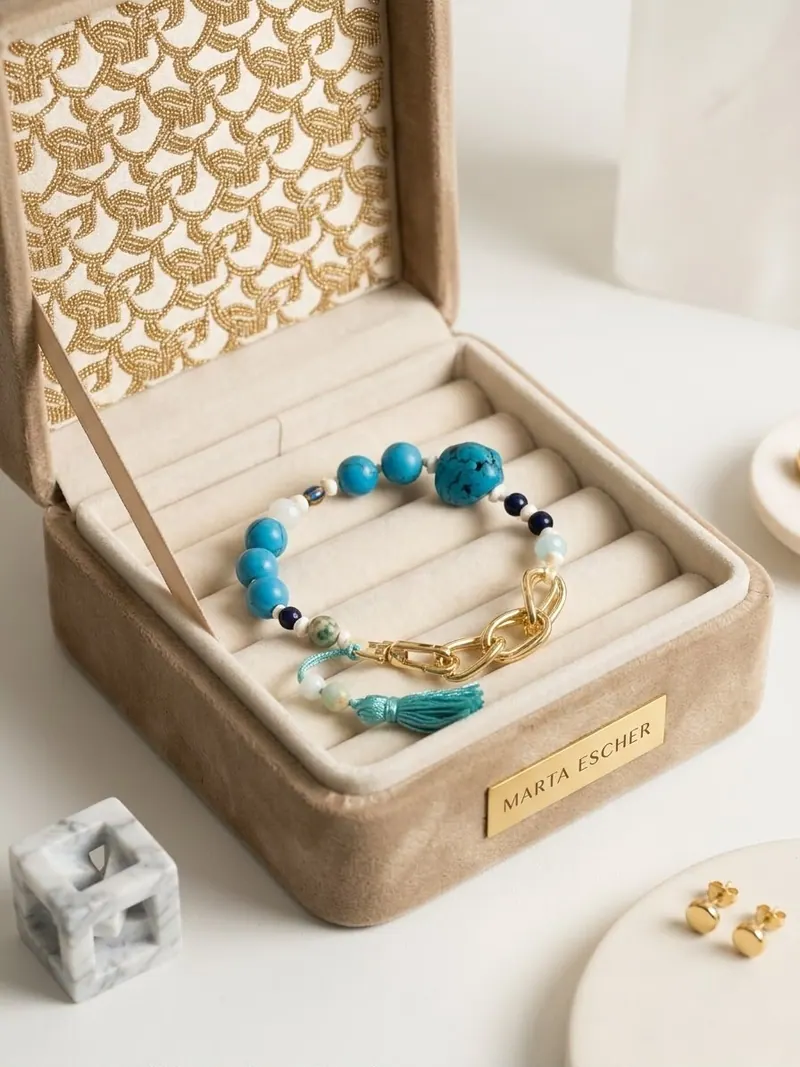 Pulseira de contas turquesa e elos dourados com borla, numa caixa de veludo com a placa Marta Escher
